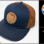Buff Daddy Coin-Patch Baseball Cap.<br/><br/>Colors: Navy, Caramel.<br/>This cap features a laser-etched, faux-suede leather patch.<br/>Richardson® #112, Original Trucker design. Adjustable.<br/><br/>